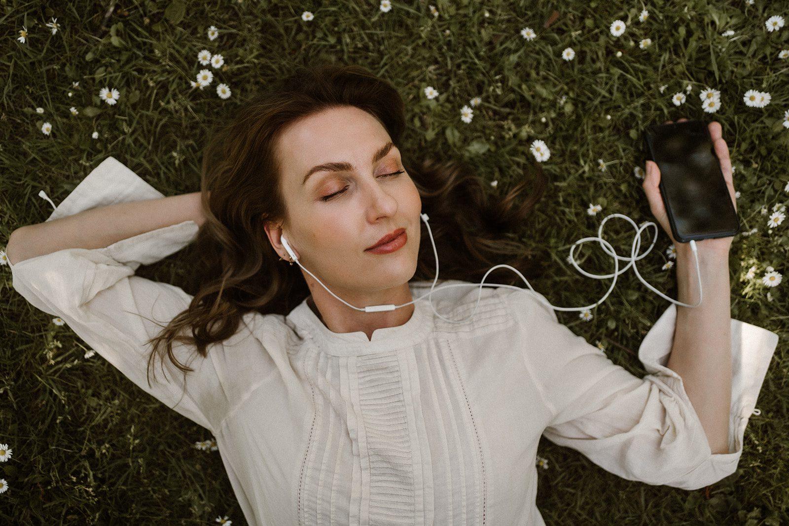 An aesthetic girl lying on the follower using hand-free to enjoy music