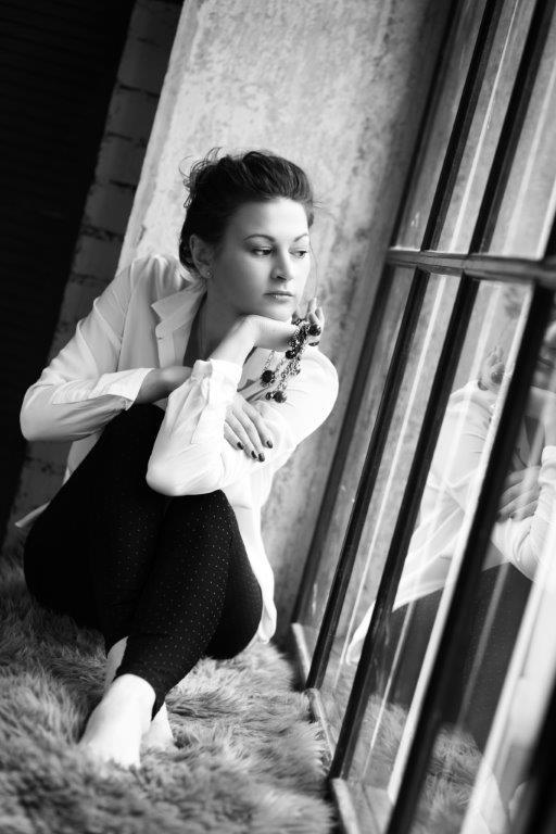 In a black, and white photo, an aesthetic girl wearing black tight sitting on the Yoga Nidra balcony