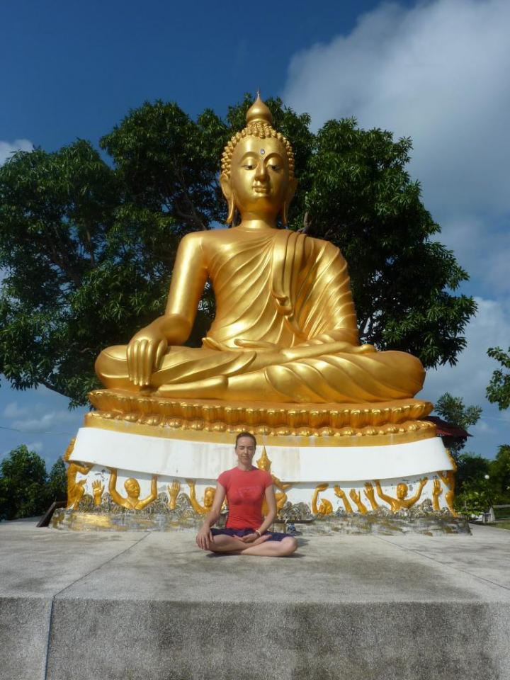 She is sitting below a golden Buddha statue, capturing the beauty and power of nature in all its glory.