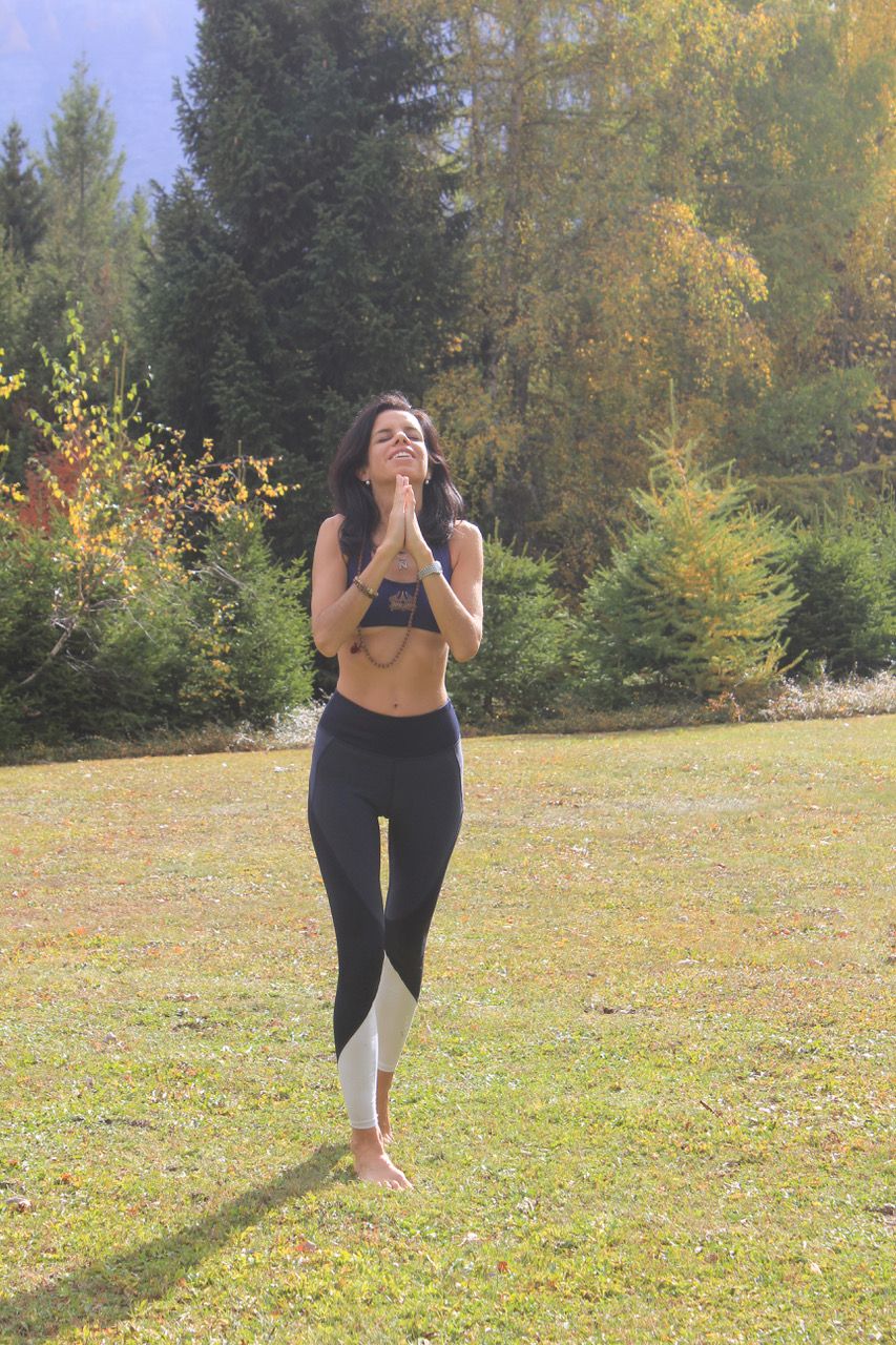 A Woman practicing yoga wearing black trousers, with her face turned upward