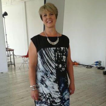 The short-haired adult woman wearing a necklace and black yoga dress
