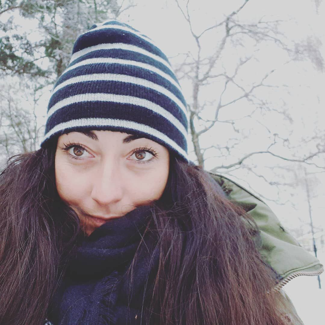 A young girl enjoying winter snowfall who her long hair and wearing a cap