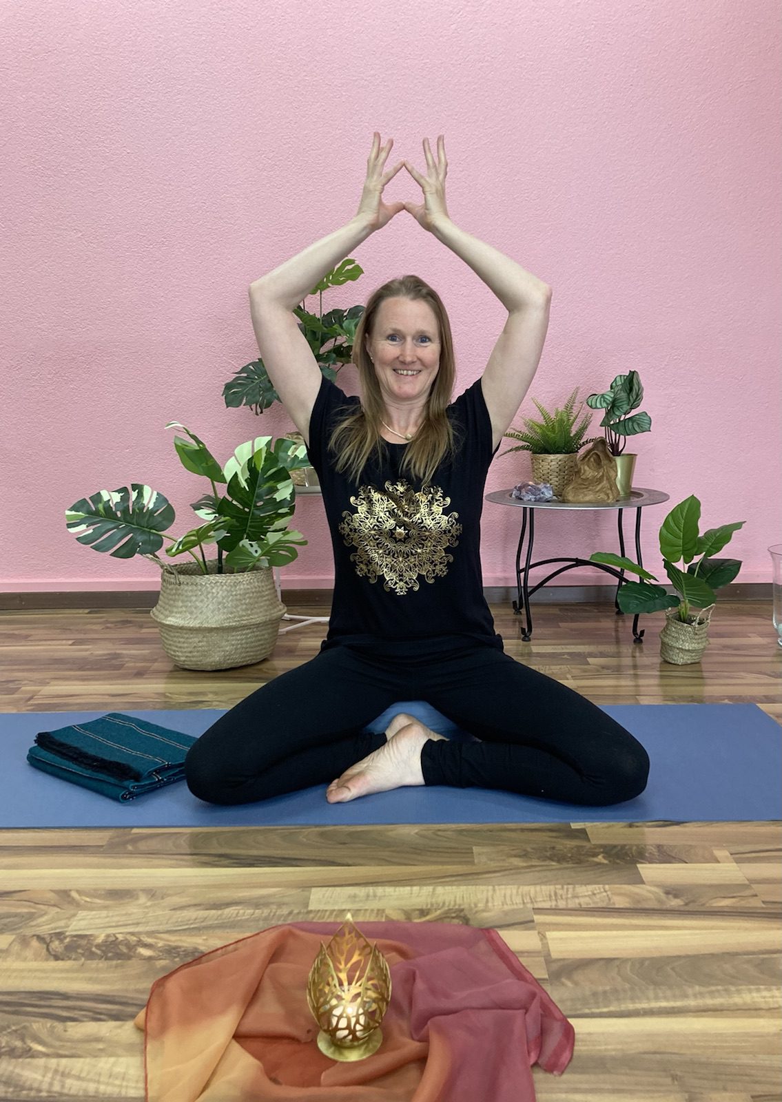 A female yoga instructor sitting with an easy pose on the mat and with her flip hands upward